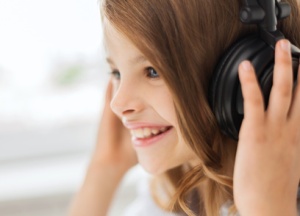 smiling little girl with headphones at home